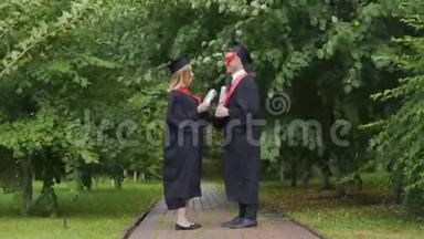 风和日丽的天气，一对毕业生拿着毕业证书站在公园里，变化的风